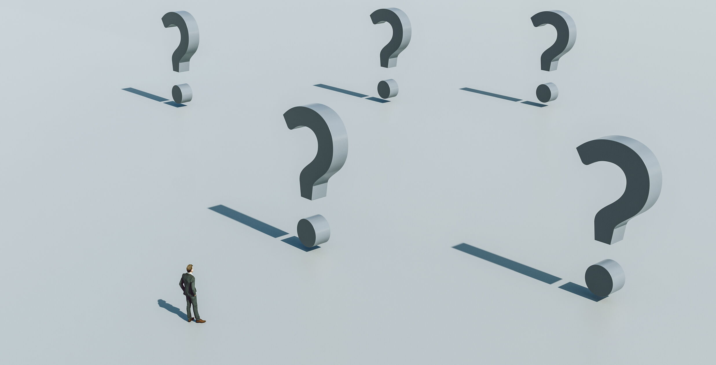 Ein Mann steht auf einer grauen Fläche, umgeben von übergroßen 3D-Fragezeichen, die lange Schatten werfen. Die Szene vermittelt ein Gefühl von Nachdenken oder Unsicherheit.